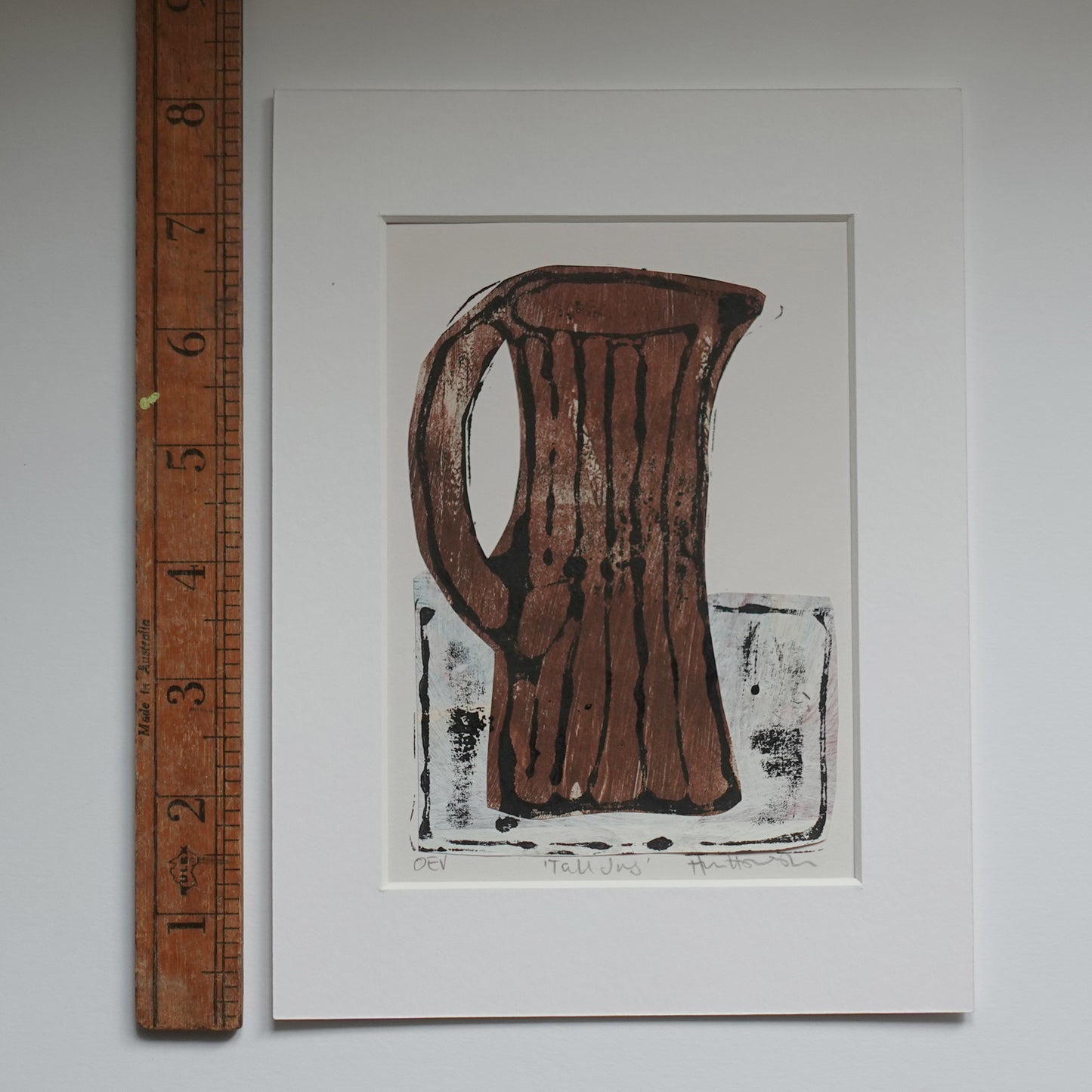 Relief print of tall jug, printed in black ink over chine-collé shown in mount with wooden ruler for scale
